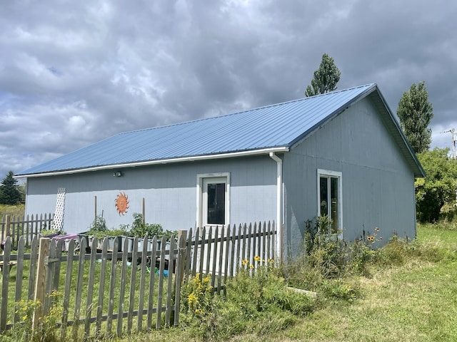 view of side of home with fence and metal roof