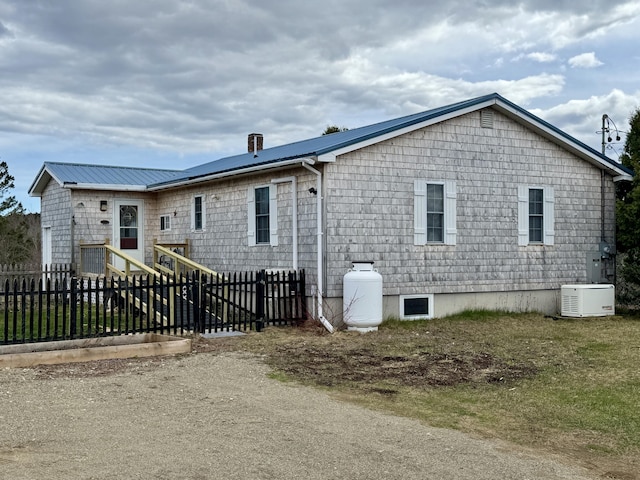 view of side of property featuring metal roof and fence