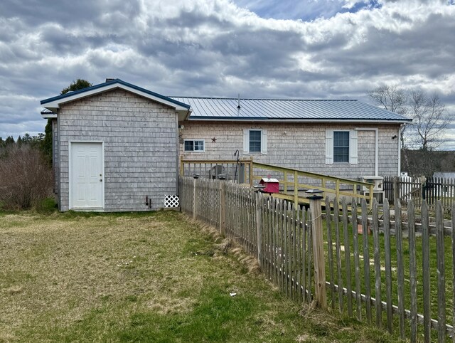 back of house featuring a lawn, a fenced backyard, and metal roof