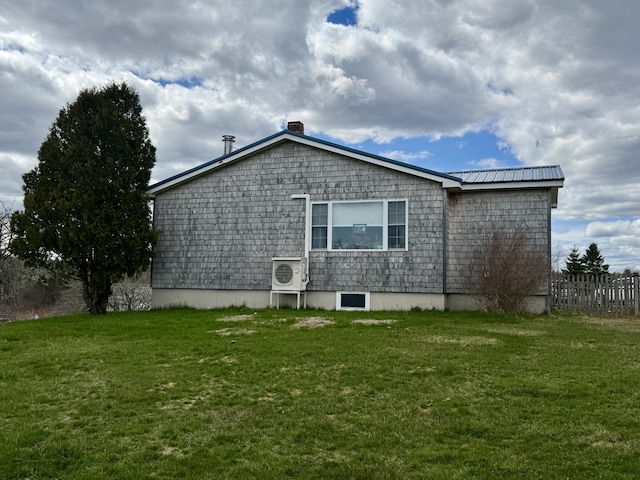 view of side of home featuring fence, a chimney, and a yard