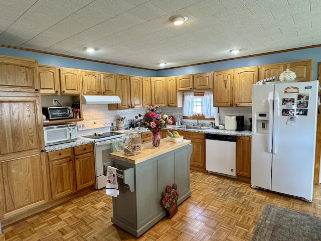 kitchen with decorative backsplash, white appliances, a sink, and under cabinet range hood