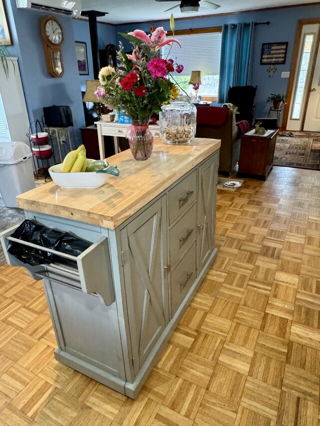 kitchen with an AC wall unit, butcher block countertops, and a wood stove