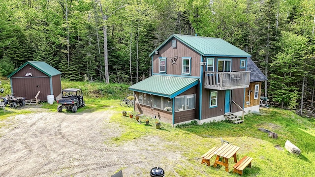 view of front of house featuring entry steps, driveway, and a wooded view
