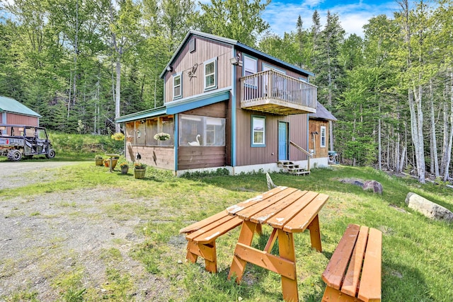 rear view of property featuring a forest view, a balcony, and entry steps