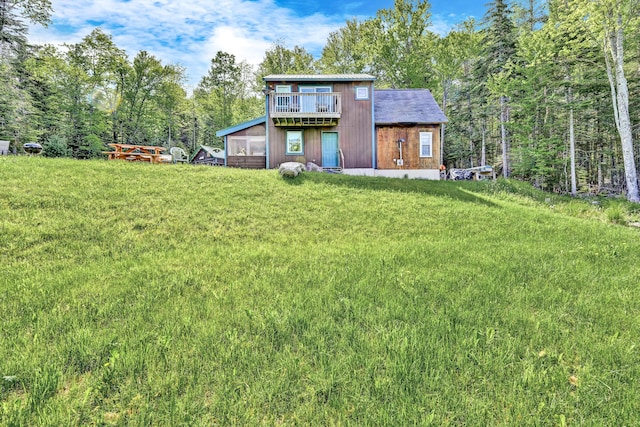 rear view of house featuring a lawn, a sunroom, and a forest view