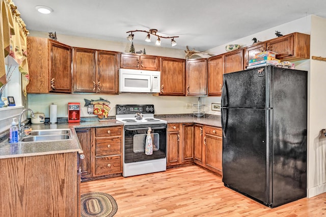 kitchen featuring range with electric stovetop, a sink, freestanding refrigerator, white microwave, and light wood-style flooring