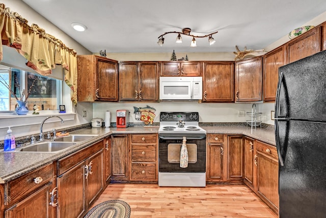 kitchen featuring freestanding refrigerator, light wood-style floors, white microwave, electric stove, and a sink
