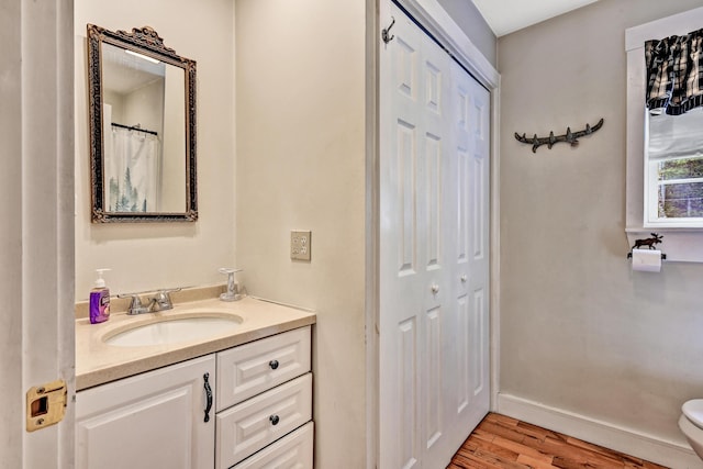 bathroom with vanity, baseboards, wood finished floors, and toilet