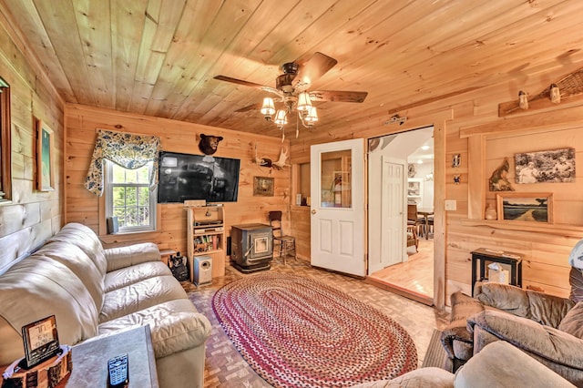 living area with a ceiling fan, wood walls, wood ceiling, and a wood stove