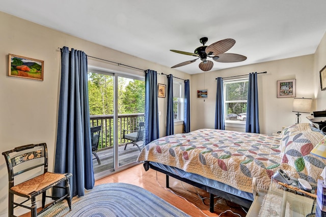 bedroom with ceiling fan, wood finished floors, multiple windows, and access to exterior