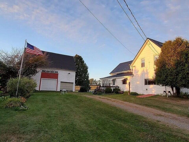 view of side of property featuring driveway, a yard, and a garage
