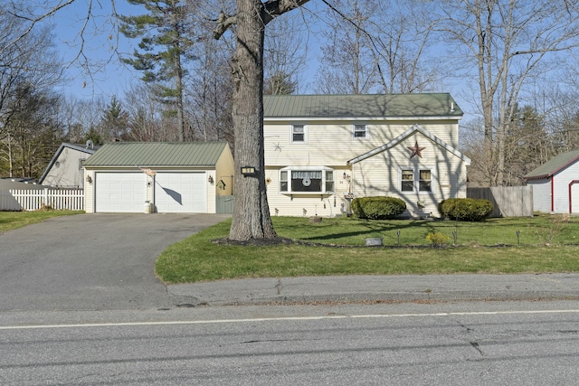 view of front of property with an outbuilding, driveway, fence, an attached garage, and a front yard