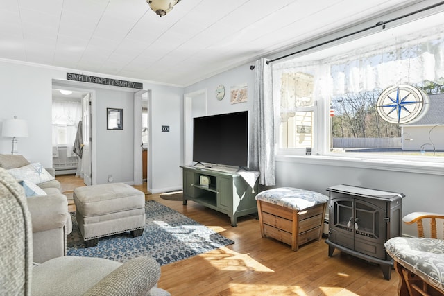 living room with a baseboard radiator, wood finished floors, a wood stove, and crown molding