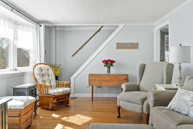 living area with stairway, crown molding, baseboards, and wood finished floors
