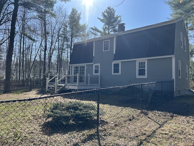 7 Kathryn St, Gorham, ME 04038 - rear view of house featuring a gambrel roof, a wooden deck, a fenced backyard, and a chimney