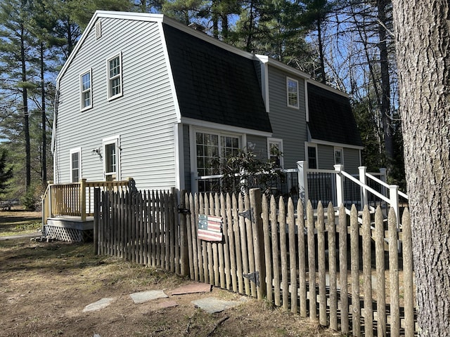7 Kathryn St, Gorham, ME 04038 - view of front facade featuring roof with shingles, a wooden deck, fence private yard, and a gambrel roof