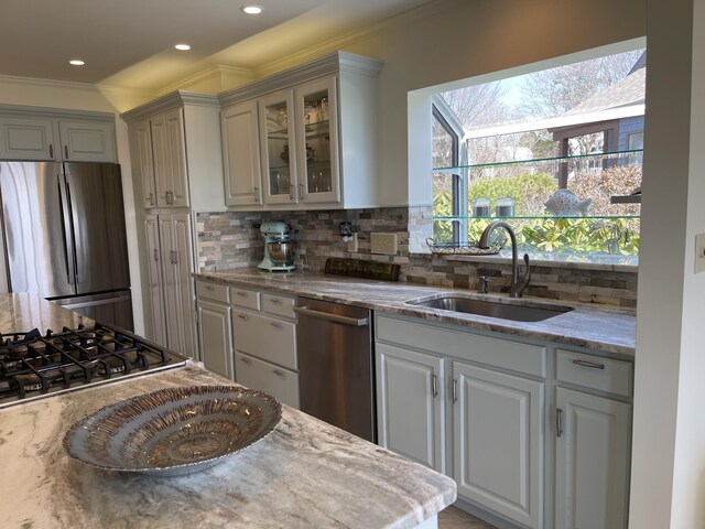 kitchen with backsplash, appliances with stainless steel finishes, ornamental molding, and a sink