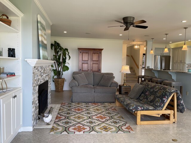 living room with recessed lighting, a ceiling fan, stairs, a tile fireplace, and ornamental molding