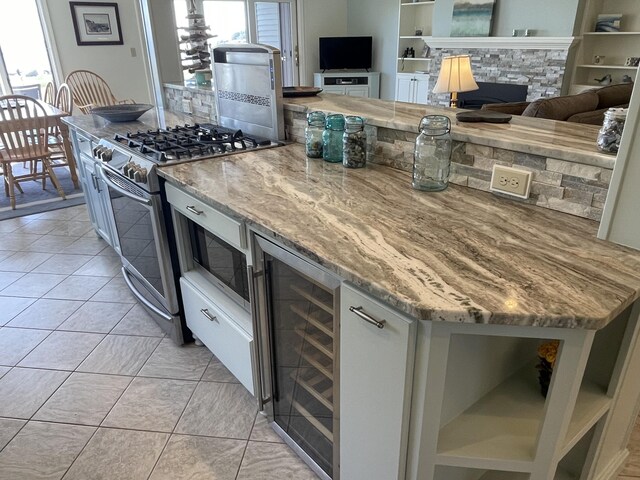 kitchen featuring light stone countertops, stainless steel range with gas stovetop, beverage cooler, and open floor plan