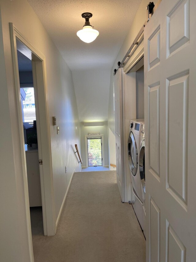 laundry area featuring light colored carpet, a barn door, laundry area, and independent washer and dryer