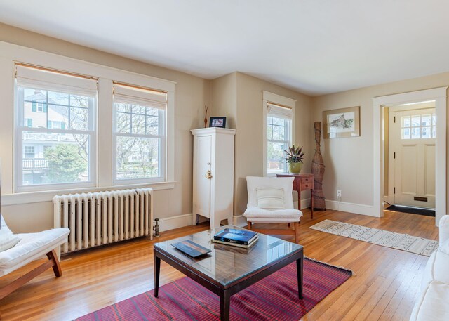 living area with light wood-type flooring, baseboards, and radiator heating unit