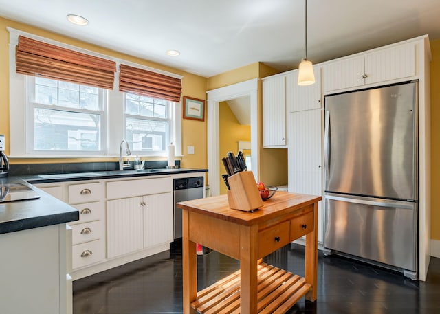 kitchen featuring a sink, appliances with stainless steel finishes, a wealth of natural light, and dark countertops