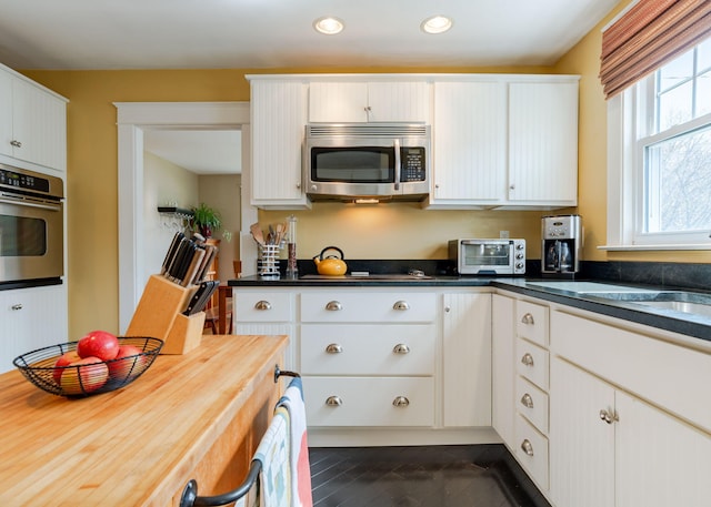 kitchen with recessed lighting, appliances with stainless steel finishes, white cabinetry, and a toaster