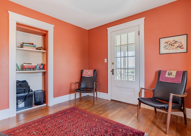 living area featuring baseboards and hardwood / wood-style floors