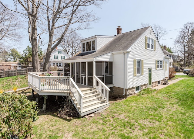 rear view of house featuring a chimney, a lawn, a deck, a sunroom, and a shingled roof