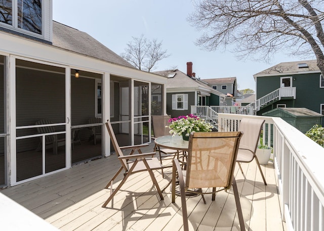 deck featuring outdoor dining area and a sunroom