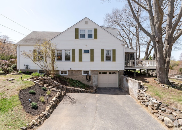 view of front of property with a garage, a wooden deck, and aphalt driveway
