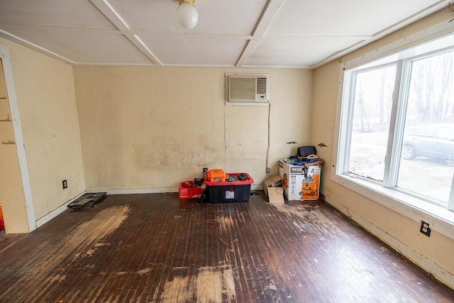 unfurnished room featuring baseboards, wood-type flooring, and a wall mounted air conditioner