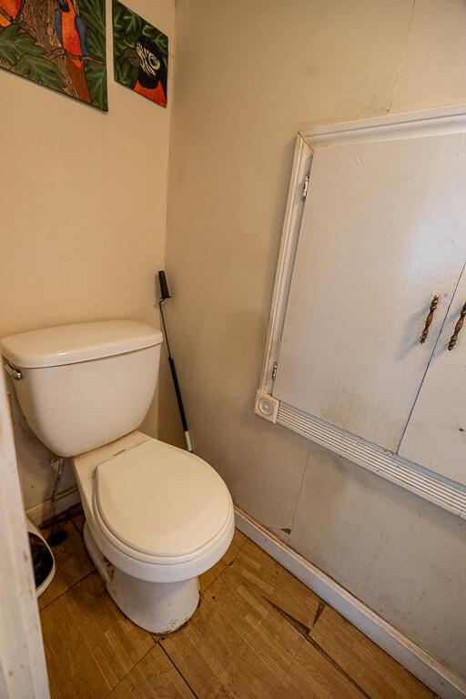 bathroom featuring baseboards, wood finished floors, and toilet