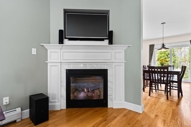 134 Yale St, Portland, ME 04103 - detailed view of baseboard heating, wood finished floors, baseboards, and a fireplace