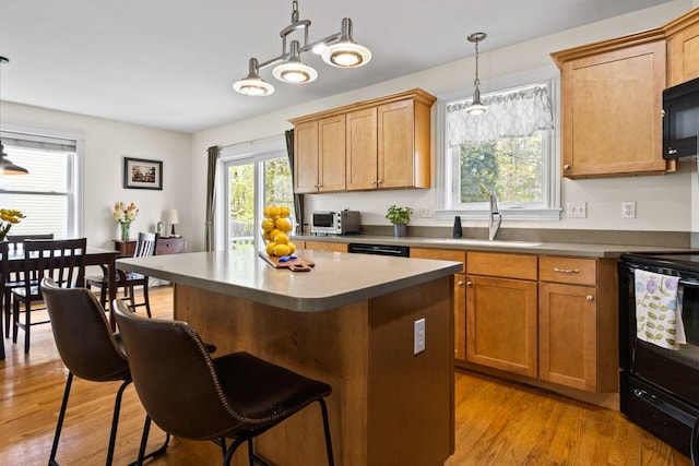 134 Yale St, Portland, ME 04103 - kitchen featuring black appliances, a sink, a kitchen bar, a center island, and light wood-style flooring