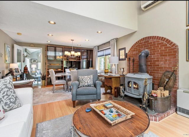 16 Howard Ave Unit 16, Wells, ME 04090 - living room with a wall unit AC, a wood stove, a notable chandelier, recessed lighting, and light wood-style flooring