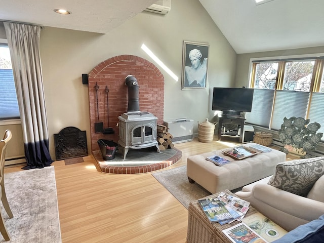 16 Howard Ave Unit 16, Wells, ME 04090 - living area with a wall mounted AC, vaulted ceiling, a wood stove, wood finished floors, and a baseboard radiator