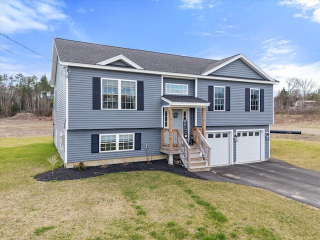raised ranch with an attached garage, roof with shingles, driveway, and a front yard