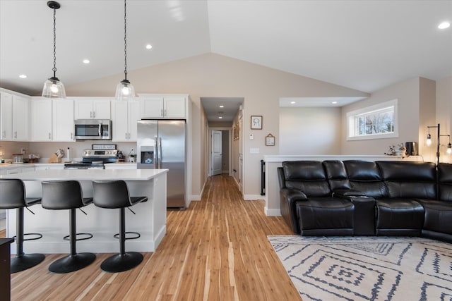kitchen with light countertops, appliances with stainless steel finishes, light wood-style flooring, and open floor plan