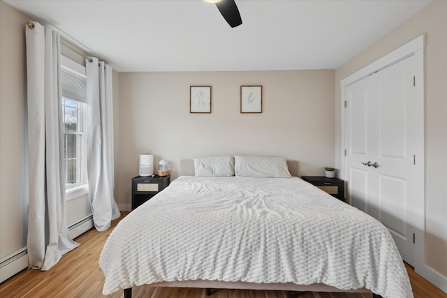 bedroom featuring ceiling fan, a baseboard heating unit, and light wood finished floors