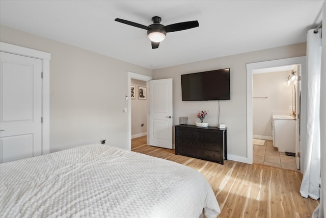 bedroom with baseboards, a ceiling fan, light wood-style flooring, and connected bathroom