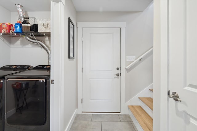clothes washing area with washing machine and clothes dryer, laundry area, baseboards, and light tile patterned floors