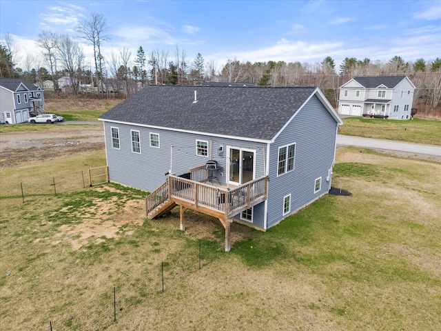 rear view of property with a yard, a deck, and roof with shingles