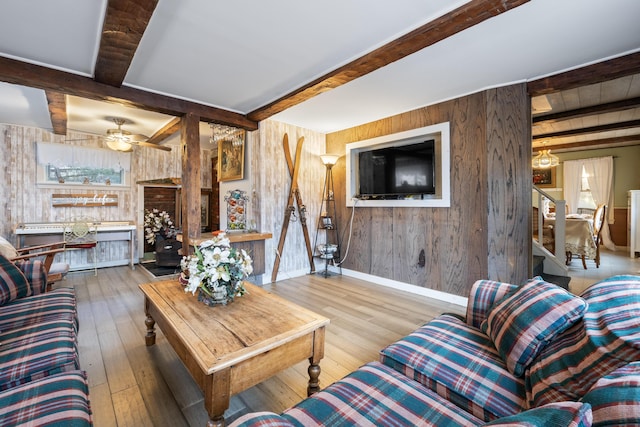 living area with wood-type flooring, wood walls, stairway, and beam ceiling