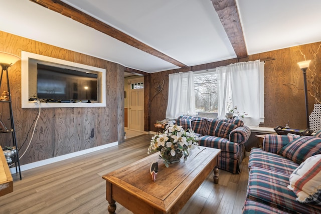 living area with baseboards, hardwood / wood-style flooring, wooden walls, and beamed ceiling
