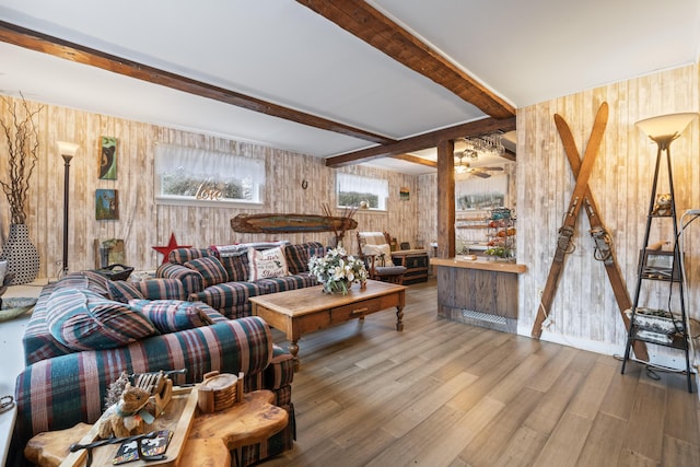 living area featuring beam ceiling, wood finished floors, wooden walls, and ceiling fan