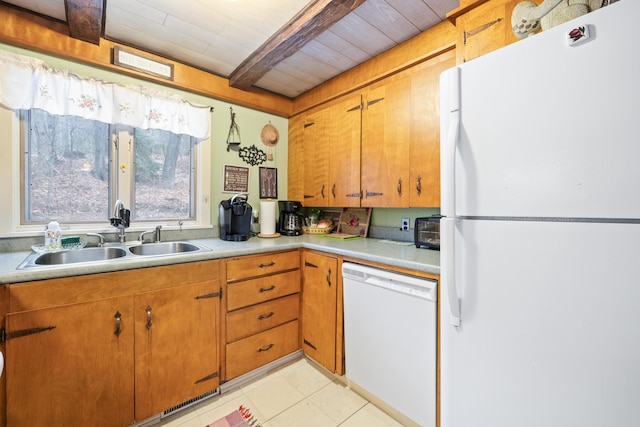 kitchen with white appliances, light tile patterned floors, light countertops, brown cabinets, and a sink