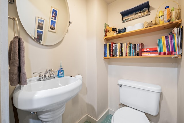 half bath featuring toilet, a sink, and baseboards