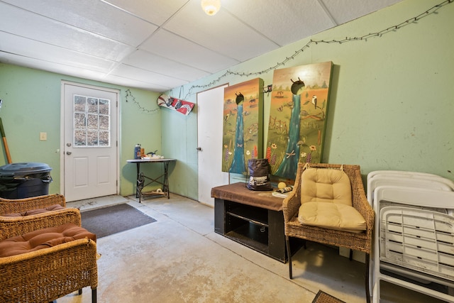 sitting room with unfinished concrete flooring and a drop ceiling