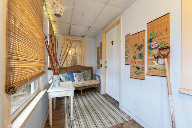 hall with a paneled ceiling and baseboards